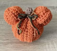 an orange crocheted mouse with a bow on it's head sitting on a wooden surface