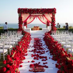 an outdoor wedding setup with red flowers and white chairs