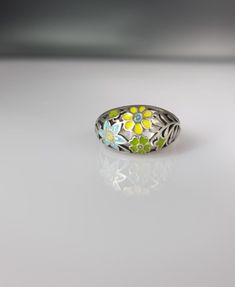 Discover the elegance of artisan craftsmanship with this exquisite 4-gram silver ring, adorned with vibrant hand-painted enamel in a charming floral pattern. Each detail is meticulously crafted to create a piece that's not only jewellery but wearable art. Perfect for adding a touch of sophistication to any outfit or as a treasured gift for someone special. Green Enamel Jewelry With Black Enamel, Yellow Enamel Ring, Oval Green Enamel Ring Gift, Flower-shaped Enamel Ring As Gift, Floral Enamel Ring As Gift, Green Enamel Wedding Jewelry, Green Enamel Jewelry For Wedding, Green Enamel Anniversary Ring, Flower-shaped Enamel Ring For Gift