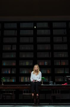 a woman sitting on a bench in front of bookshelves