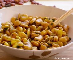 a bowl filled with chickpeas and some chopsticks next to nuts on a table