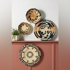 three woven baskets are hanging on the wall next to a potted plant and vase