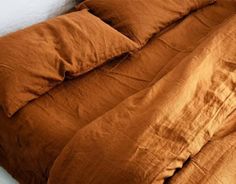 an unmade bed with brown sheets and pillows