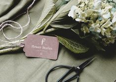 some flowers and scissors are laying on the table next to it's tag that says flower stories