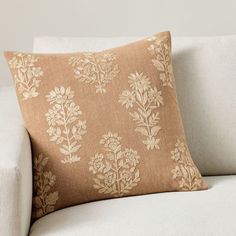 a white couch with a tan and gold pillow on it's backrests