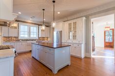 an empty kitchen with white cabinets and wood floors