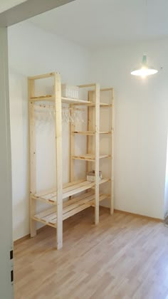 an empty room with wooden shelves and hard wood flooring on the side, in front of a white wall