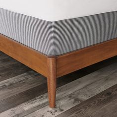 a close up view of a bed with wood frame and white sheets on the headboard