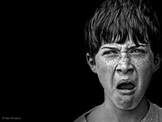 a young boy with freckles on his face is making a shocked look at the camera