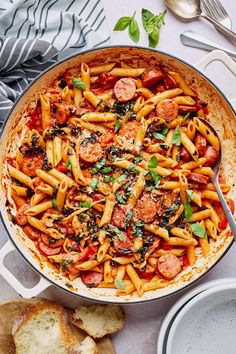 pasta with sausage and spinach in a skillet next to garlic bread on the side