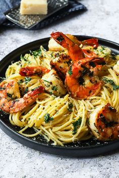 pasta with shrimp and parmesan cheese on a black plate