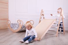 two small children playing in a room with wooden furniture and toys on the floor,