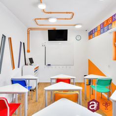 an empty classroom with white tables and colorful chairs