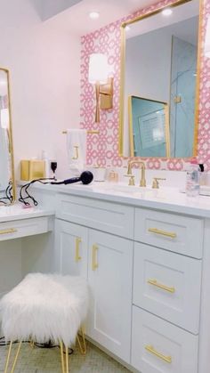 a white bathroom with pink and gold wallpaper on the walls, vanity area and stool