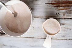 a spoon is sitting next to a bowl with something in it on a wooden table