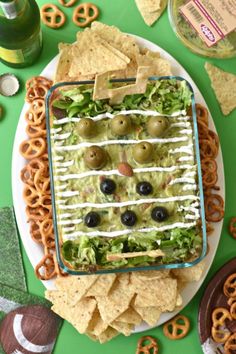 a football themed appetizer on a plate with pretzels and crackers