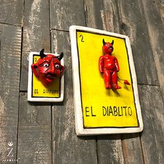 two red devil magnets sitting on top of a wooden table next to each other