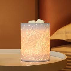 a lit candle holder sitting on top of a white table next to a brown wall