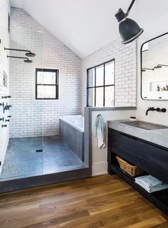 a bathroom with white brick walls and wood flooring on the wall, along with a walk in shower