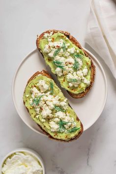 two pieces of bread with avocado and cottage cheese on them next to a bowl of yogurt