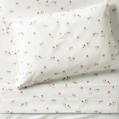 a white sheet with red and green designs on it is next to a pillow case