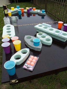 an outdoor table with cups and bowls on it