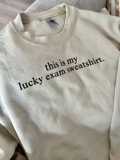 this is my lucky exam sweatshirt on a couch with the words'this is my lucky exam sweatshirt'printed on it