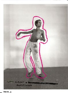 a man standing in front of a white wall with pink paint on his body and arms