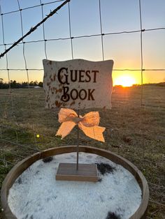 a sign that says guest book sitting on top of a barrel in front of a fence