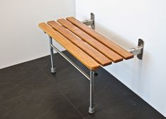 a wooden bench sitting on top of a black tile floor next to a white wall