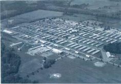 an aerial view of a parking lot in the middle of a large field with many buildings