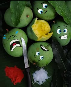 some green fruit with faces painted on them next to a knife and powdered sugar