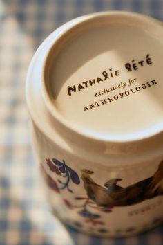 a close up of a cup on a checkered tablecloth with the name nathanie giff