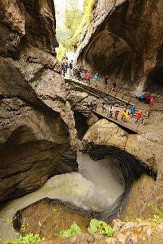 several people are walking up and down the stairs into a cave that is filled with water