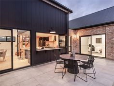 an outdoor dining area with table and chairs next to the house's large glass doors