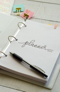 an open planner and pen sitting on top of a table