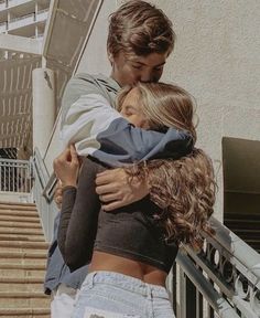 a man and woman hug each other on the steps