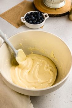 a white bowl filled with batter and blueberries