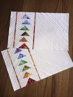 three quilted placemats sitting on top of a wooden table next to each other