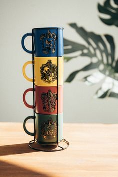 four harry potter mugs stacked on top of each other in front of a plant