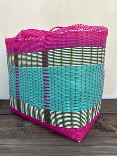 a pink and blue basket sitting on top of a wooden floor