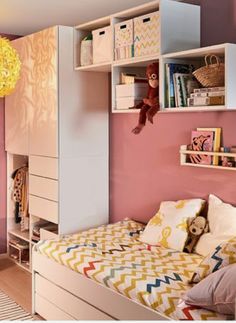 a child's bedroom with pink walls, white furniture and colorful accessories on the shelves