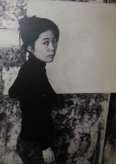 black and white photograph of a woman standing in front of a painting