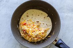 a tortilla with shredded cheese in a skillet