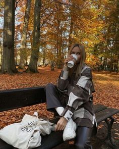 a woman sitting on a bench drinking from a cup