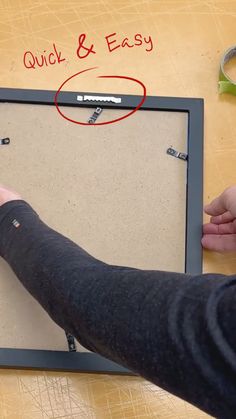 Picture of a person taking the picture frame off the workbench where they just installed a sawtooth hanger on the back of the picture frame. Quick and Easy is printed in red with a circle around the hanger. Picture Hangers Ideas, How To Easily Hang Pictures On Wall, Tips For Hanging Pictures On The Wall, How To Hang Pictures On Wall, Framing Canvas Art, Art Hanger, Framing Canvas