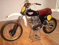 a motorcycle is parked on a stand in the middle of a room with hardwood floors