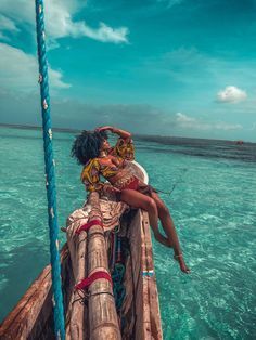 two women sitting on the back of a boat in clear blue water, while one woman holds her head