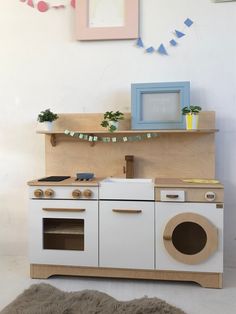 a play kitchen with an oven, sink and potted plant