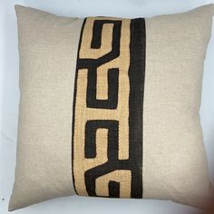 an embroidered pillow with the word go on it in black and tan colors, sitting on a white surface